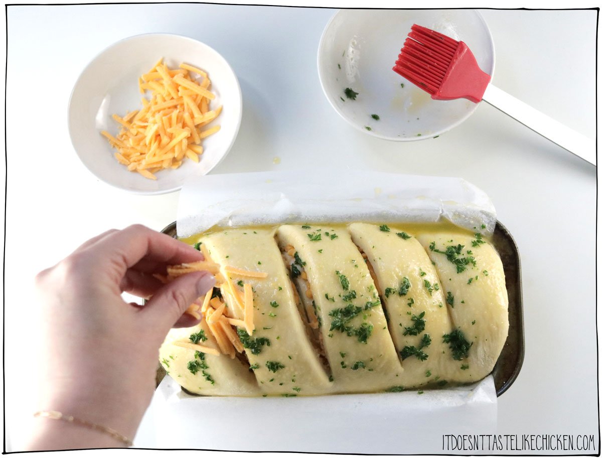 Once the bread has risen, top with the butter, garlic, parsley, and more cheese.